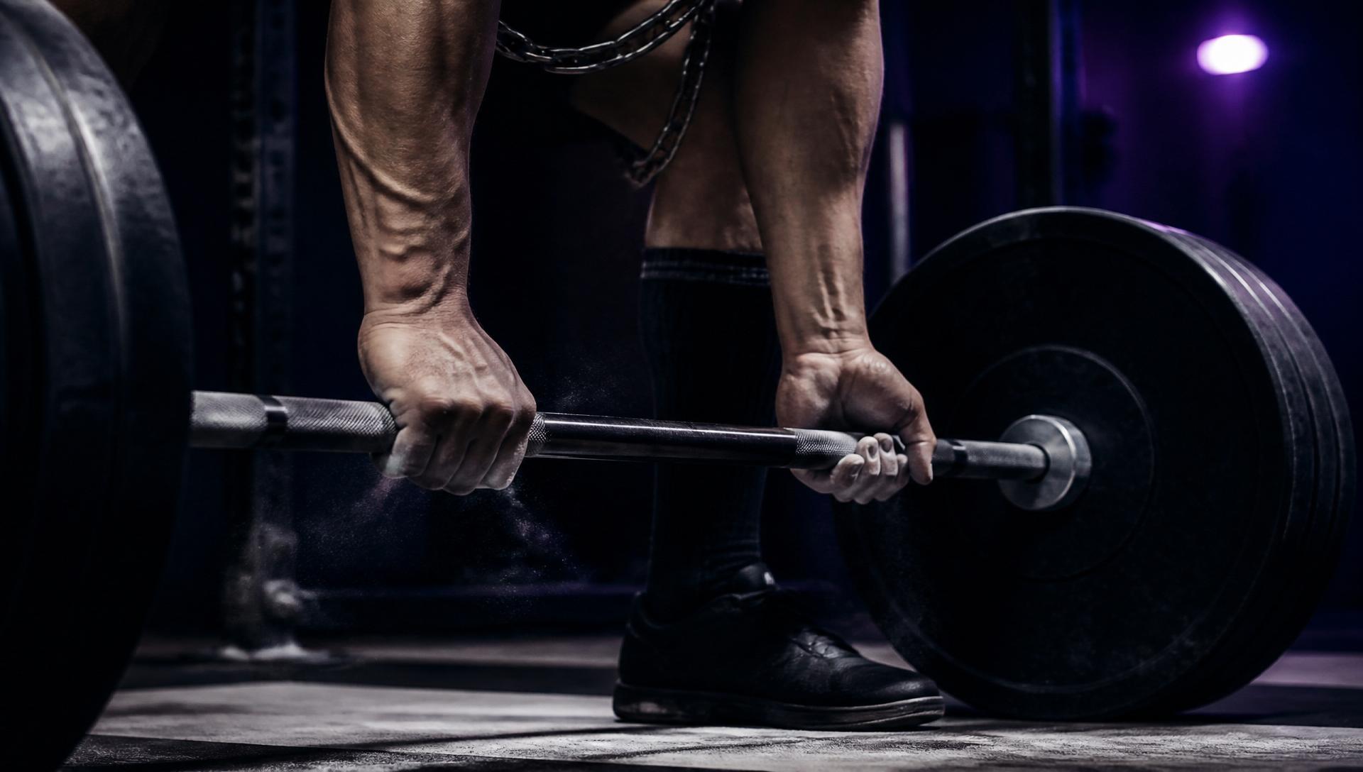 Close-up of a barbell loaded with plates ready for a heavy deadlift in a dramatic gym