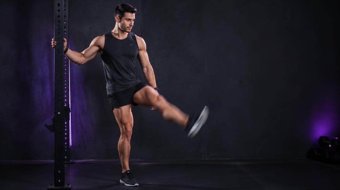 Front-to-Back Leg Swings: Man holding a rack upright and swinging one leg forward under control