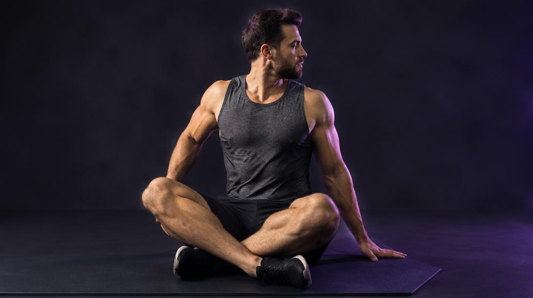 Seated Thoracic Rotation: Man sitting cross-legged, rotating his upper back to look over one shoulder