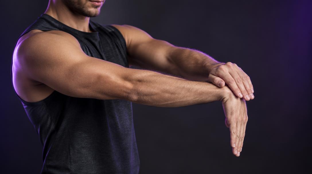 Wrist Extensor Stretch: Man extending one arm with the palm down, gently pressing the back of the hand down